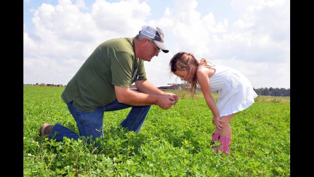 Charles Fletcher of Edgewood Dairy and Creamery tells his granddaughter about the value of good grazing forage. Photo courtesy of Edgewood Dairy